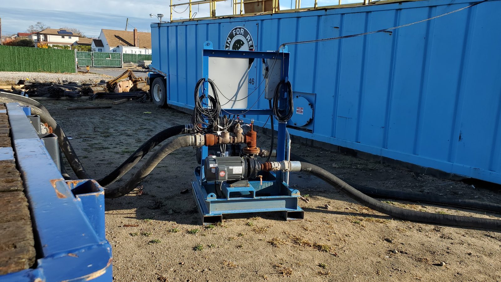 Skid-mounted dewatering pump system with intake and discharge hoses connected on a construction site