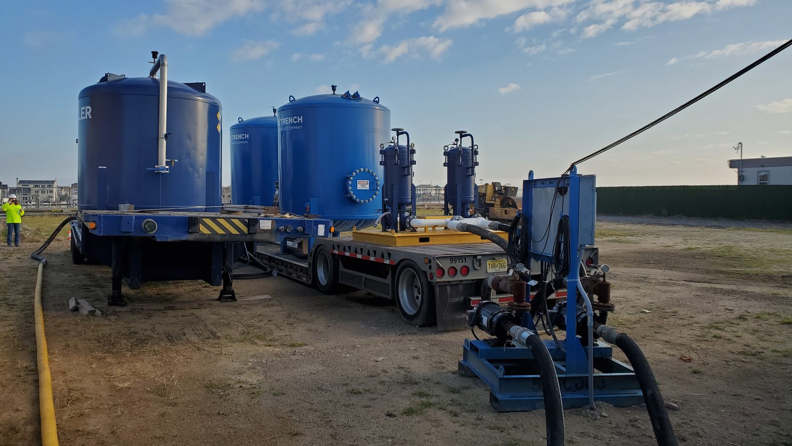 Trailer-mounted groundwater treatment tank with access stairs and platform, part of a construction dewatering treatment train